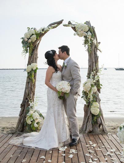 bride and groom under driftwood arch at Sam's Chowder House beach wedding