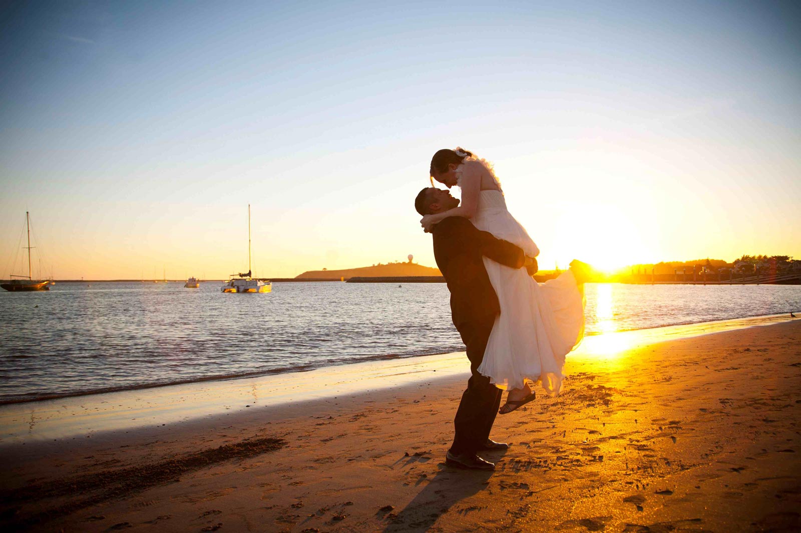 newlywed couple on beach at sunset in front of Sam's Chowder House during oceanfront wedding reception