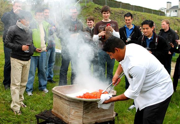 Chef removes Maine lobster from steamer box on Sam's lawn during corporate event